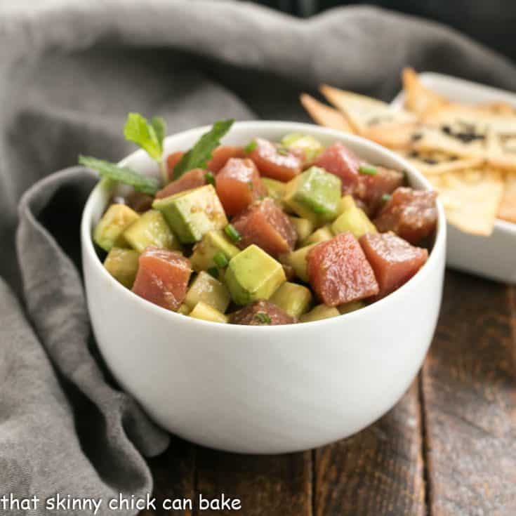 Tuna tartare with avocados in a white ceramic bowl in front of a small bowl of wonton chips