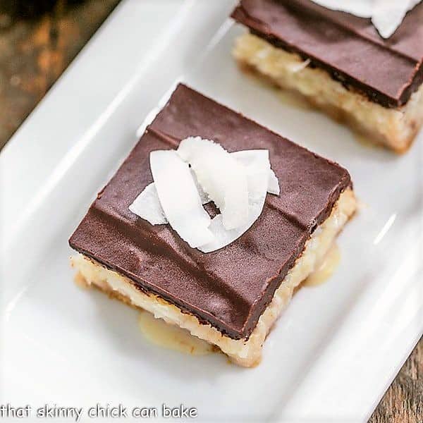 Coconut Chocolate Bars garnished with shaved coconut on a white tray.