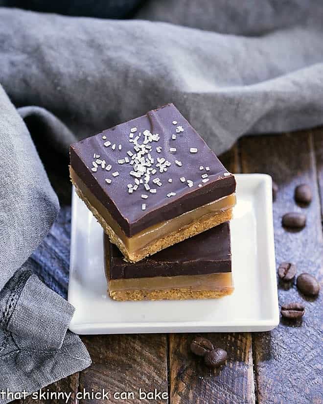 Caramel espresso bars stacked on a small square white plate.