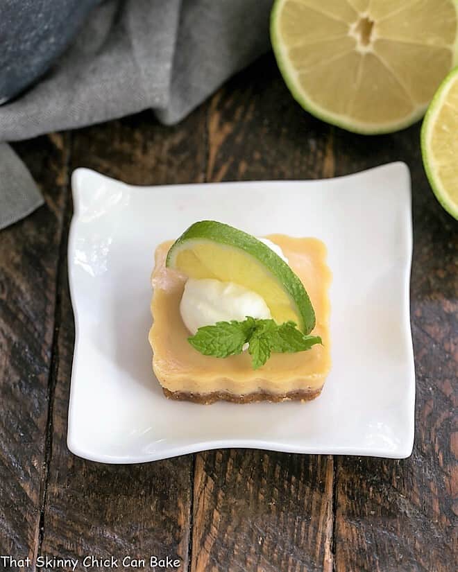 Key Lime Tartlet on a white plate with whipped cream and a slice of lime.