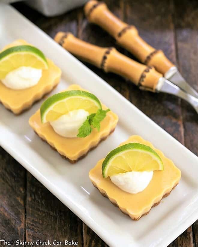 Overhead view of lime tarts on a white ceramic tray.