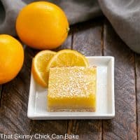 A Meyer Lemon Bar on a square white plate with lemon slices to garnish