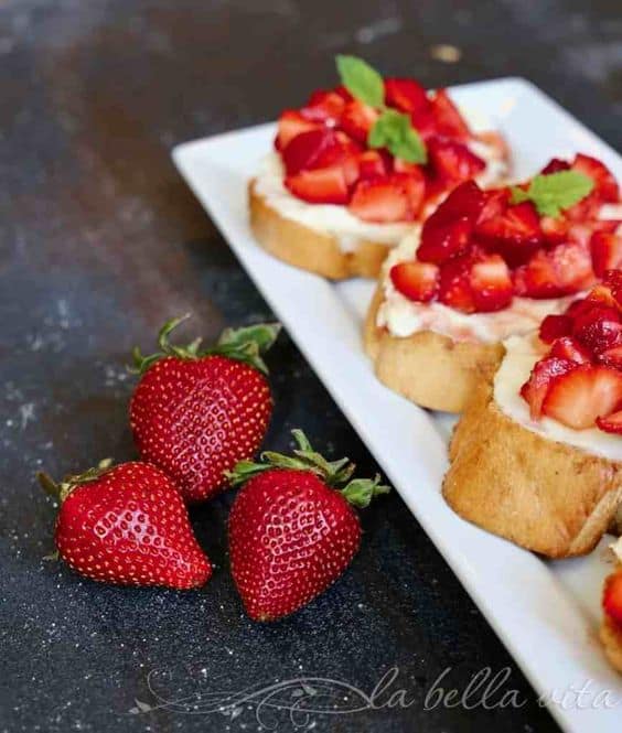 tray of strawberry crostini with 3 fresh berries