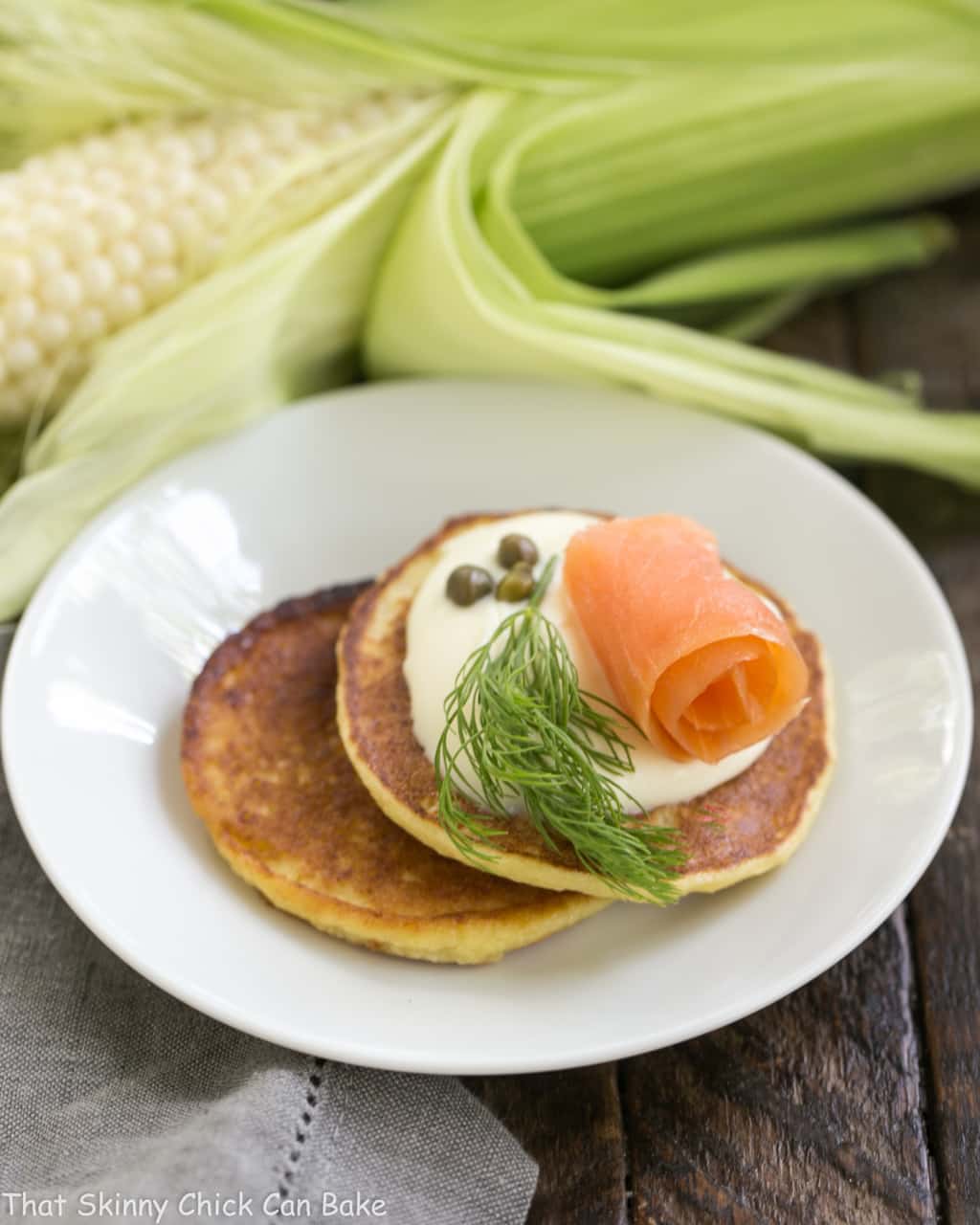 Savory Corn Cakes on a round white plate with toppings.