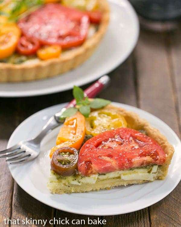 Slice of Fresh Tomato Tart on a small white plate with a red handled fork