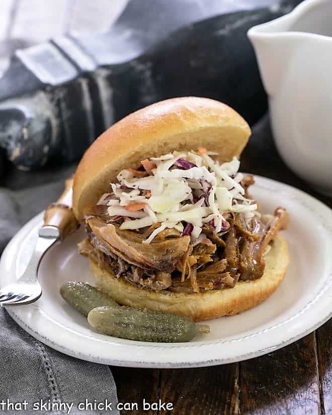 Pulled Pork Sandwiches - Slow roasted pork with an amazingly flavorful dry rub is shredded and mixed with a vinegar based BBQ sauce Pulled Pork Sandwiches topped with slaw on a round white plate.