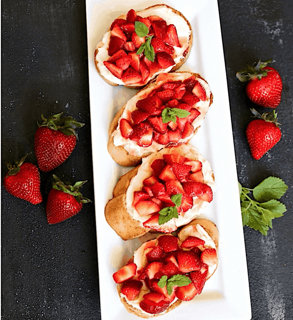 Overhead view of white tray with strawberry crostini