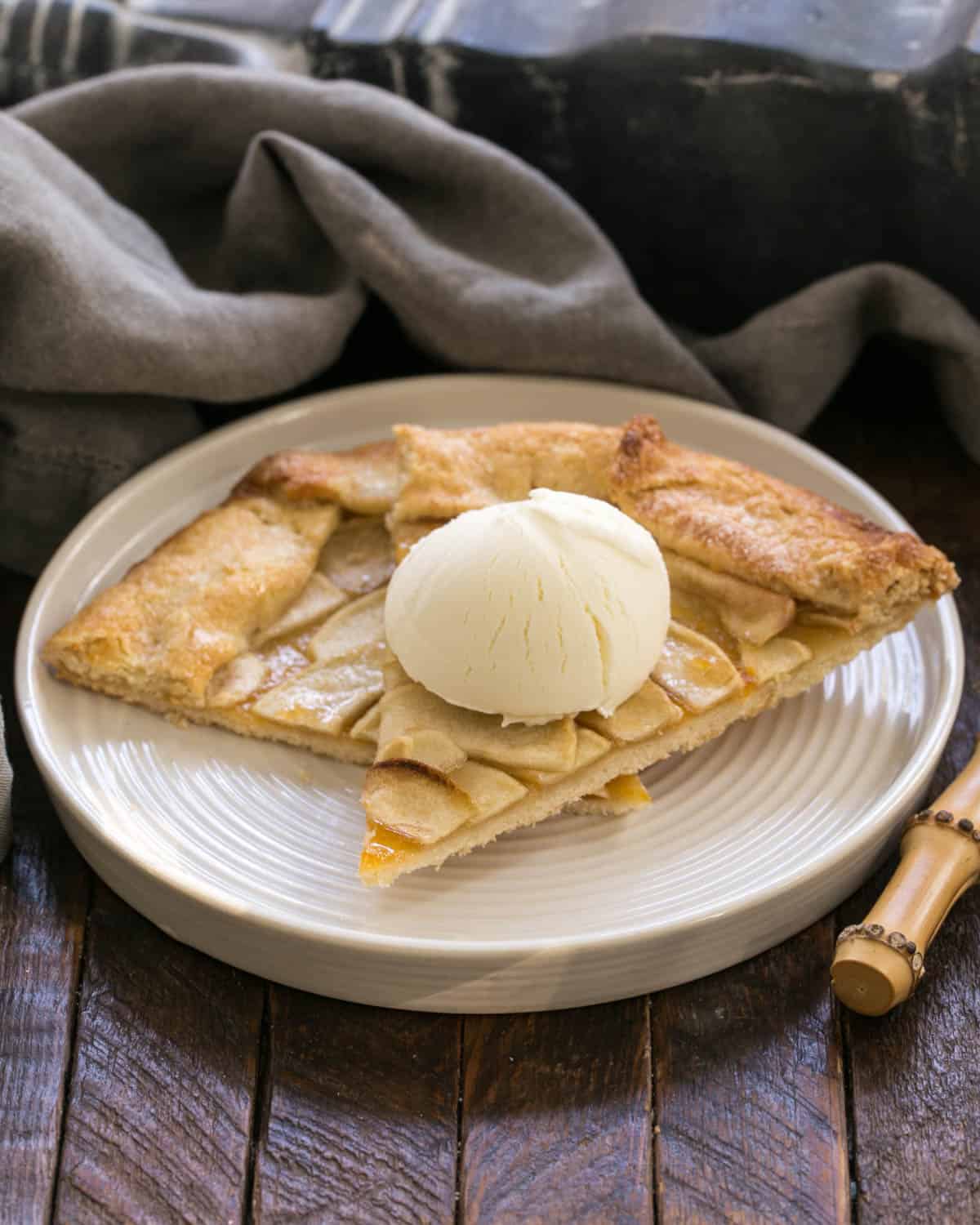 Dvije kriške kolača od jabuka na bijelom tanjuru s kuglicom sladoleda.