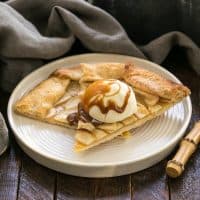 2 slices of apple crostata with a scoop of vanilla ice cream and caramel sauce