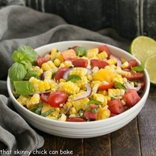 Fresh corn basil and tomato salad in a white serving bowl