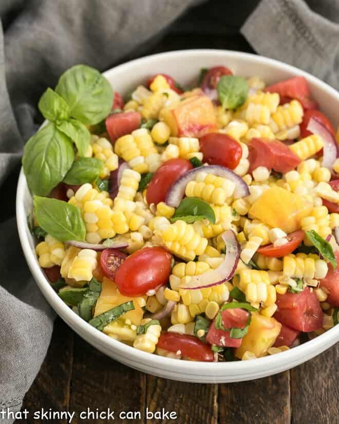 Overhead view of fresh corn and tomato salad in a white serving bowl.