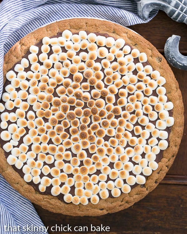 Overhead view of a S'mores Cookie Cake with a blue and white striped napkin.