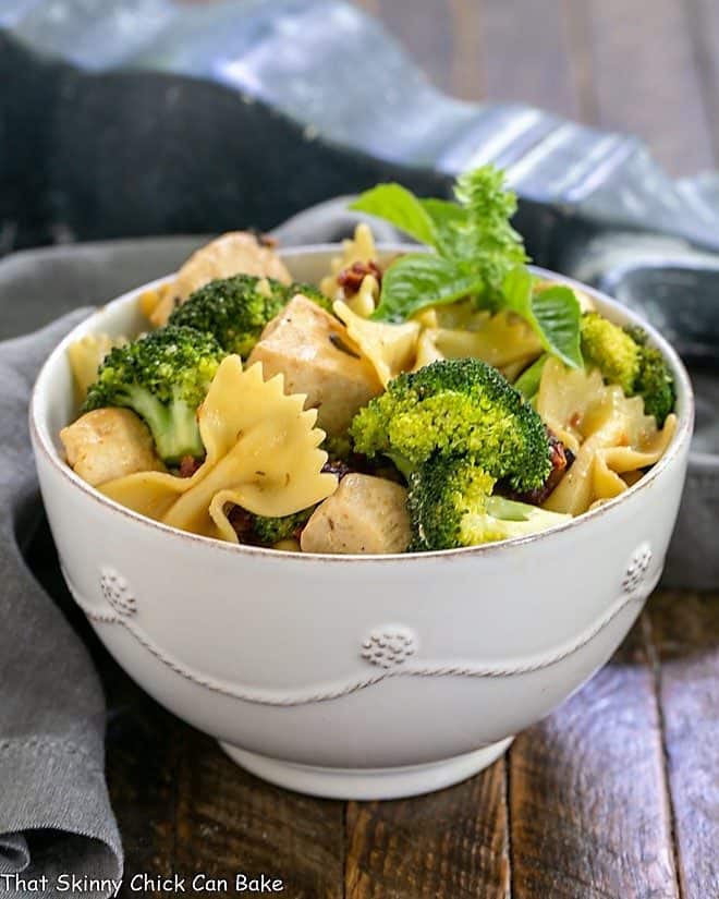 Chicken with Broccoli, Sun-dried Tomatoes and Bow Tie Pasta in a white ceramic bowl