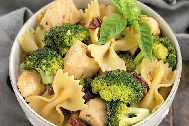 Overhead view of Chicken with Broccoli, Sun-dried Tomatoes and Bow Tie Pasta in a white ceramic bowl