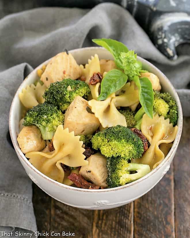 Overhead view of Chicken with Broccoli, Sun-dried Tomatoes and Bow Tie Pasta in a white ceramic bowl.