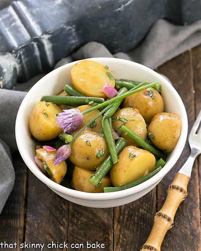 Potato and Green Bean Salad with Dijon Vinaigrette in a white bowl with a bamboo fork.