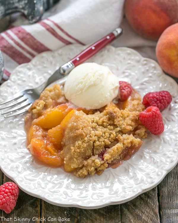 Peach Raspberry Crisp on a white plate topped with a scoop of ice cream.