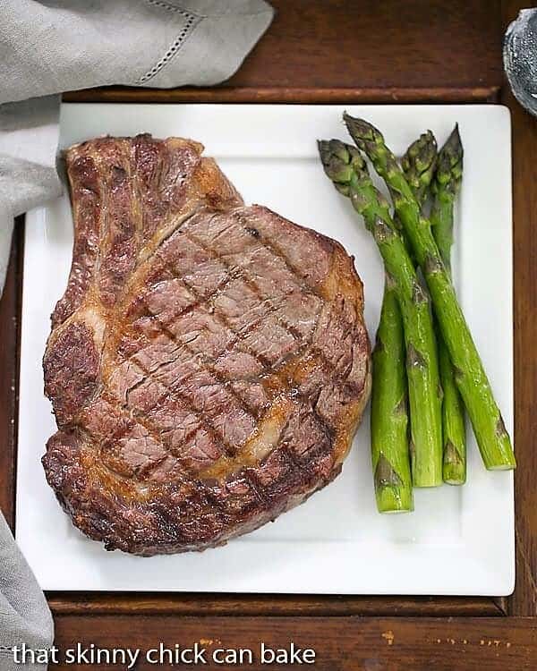  Rib Eye Steak on a dinner plate with asparagus.