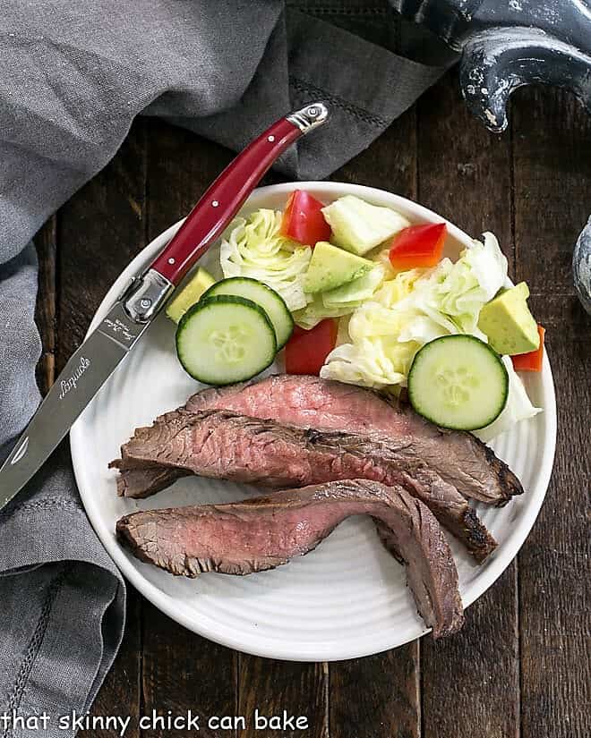 Flank steak marinated in a Soy, Orange Juice, Red Wine Marinade sliced on a round white plate.