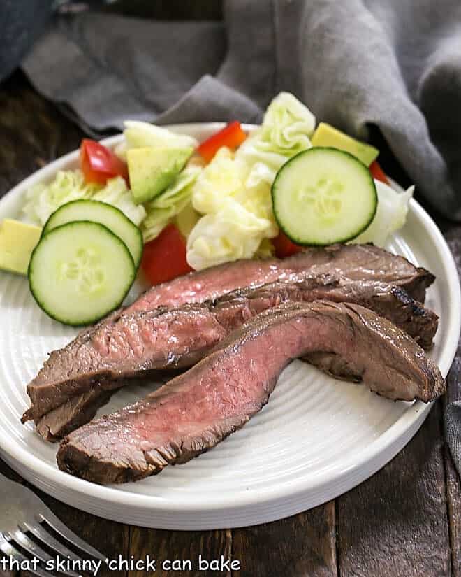 Soy, Orange Juice, Red Wine Marinade - A versatile marinade that's perfect for flank steak, chicken thighs, shrimp and more! Easy Marinated Flank Steak slices on a white plate.