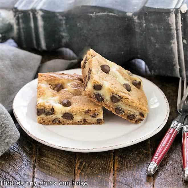 Two cheesecake filled chocolate chip bars on a round white plate