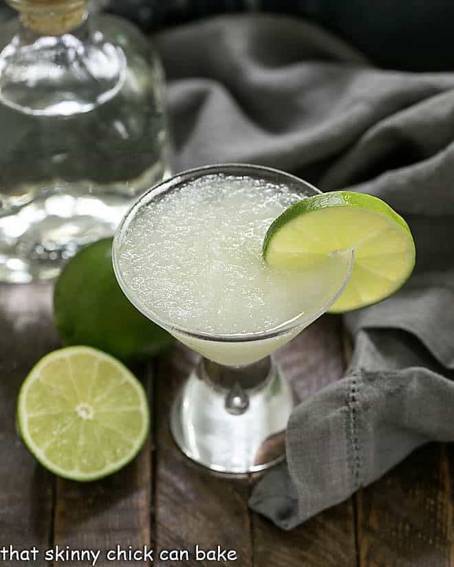 Easy 3-Ingredient Beer Margaritas with a lime garnish and tequila and limes in the background
