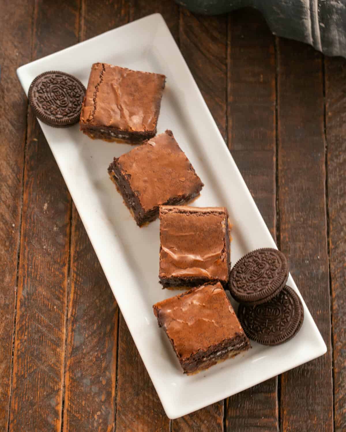 4 brownies on a white ceramic tray with Oreos to garnish.