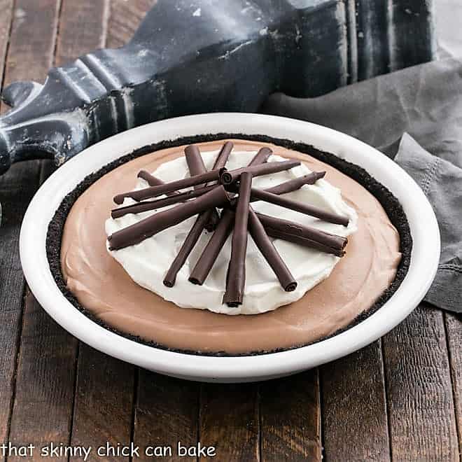 Chocolate pie in a white pie plate topped with whipped cream and chocolate curls