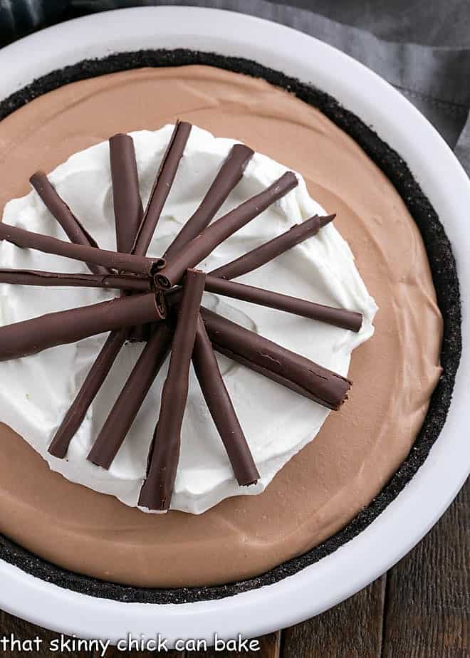 Overhead view of Candy Bar Pie garnished with chocolate and whipped cream in a white pie plate.