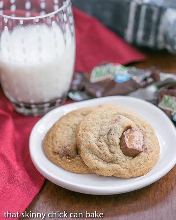 Two Milky Way Cookies chunks of Milky Way on a small white plate with a glass of milk.