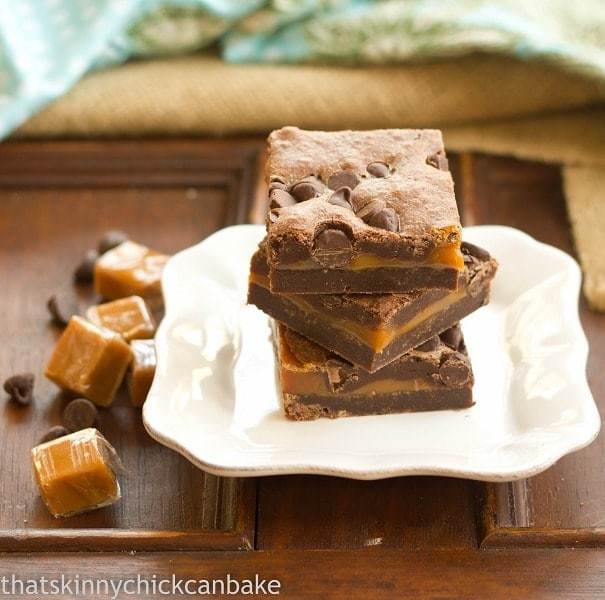 Layered Caramel Brownies stacked on a square white plate.