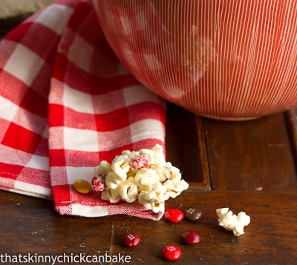 Holiday White Chocolate Popcorn in front of a serving bowl with M&M's
