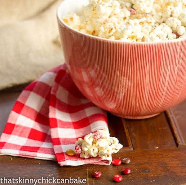 Holiday White Chocolate Popcorn in a red serving bowl with a red and white checked napkin.