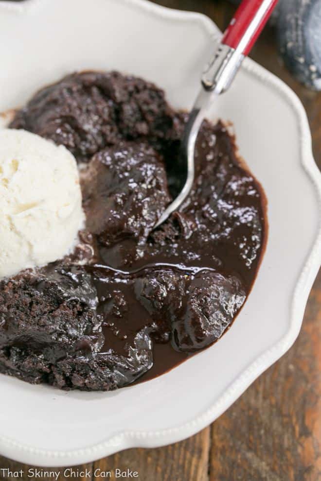 Overhead shot of Hot Fudge Pudding Cake in a white bowl with a red handled fork.