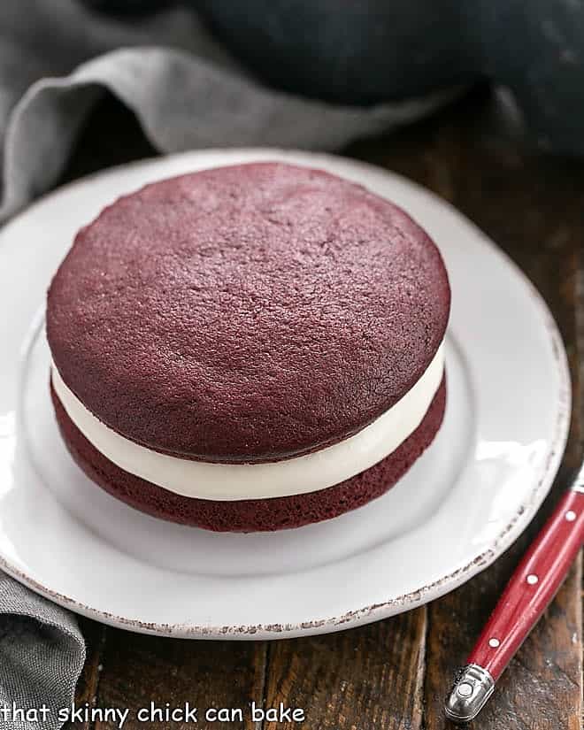 Red velvet whoopie pie on a round white plate.