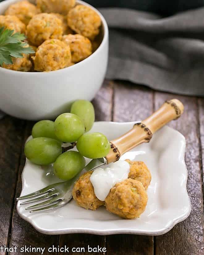 Buffalo Chicken Meatballs on a small white plate topped with blue cheese sauce