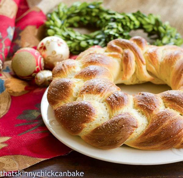 Finnish Pulla | A festive, braided Christmas bread on a white plate near holiday decorations.