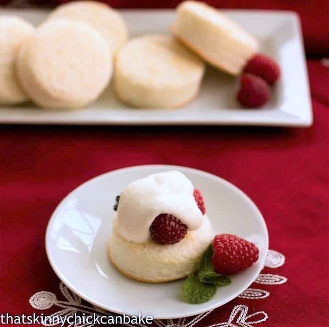 Emeril's Angel Cake Sandwiches - angel food cake rounds filled with berries and cream! Emeril's Angel Cake Sandwich without a top on a white plate with a raspberry garnish
