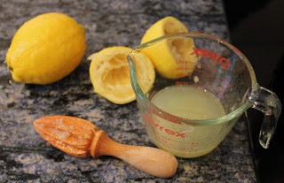 Lemon juice, reamer and lemons on a counter