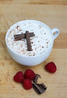 Chocolate tiramisu in a coffee cup garnished with chocolate curls, cocoa and fresh raspberries.