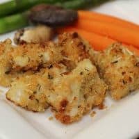 Baked chicken nuggets on a square white plate with vegetables
