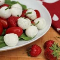 White oval platter of mozzarella, tomato and strawberry salad