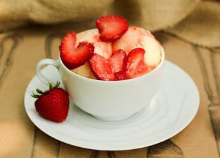 A bowl of cheesecake ice cream topped with fresh strawberry slices