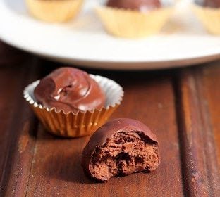 Chocolate truffle with a bite removed in front of more truffles