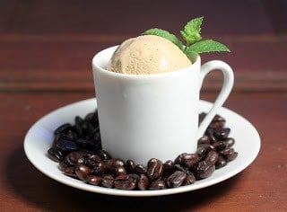 Two scoops of coffee ice cream in a coffee mug with a sprig of mint