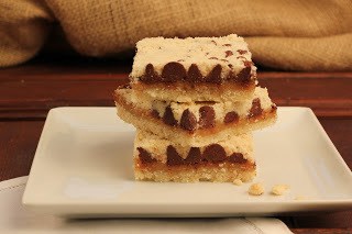 Side view of a stack of chocolate caramel streusel bars on a white plate.