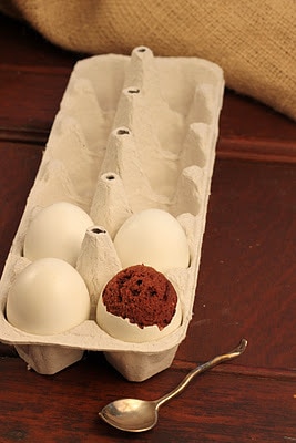4 eggs in a ceramic crate with one revealing brownie egg inside
