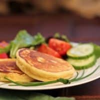 Fluffy potato pancakes on a white plate with a salad