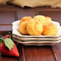 Cream puffs on a stack of white plates with fresh raspberries