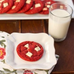 Red velvet cookie on a white plate with a glass of milk
